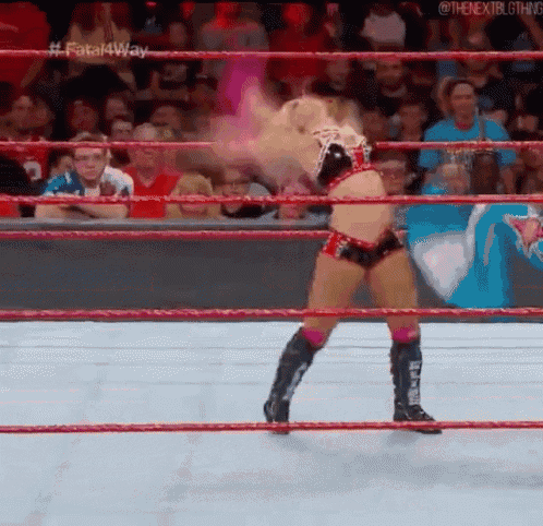 a woman is standing in a wrestling ring with her hair blowing in the wind .