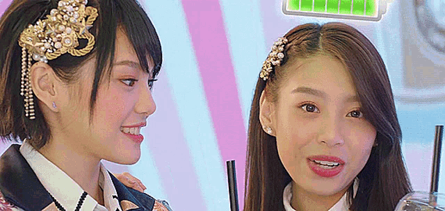 two girls are standing next to each other with straws in their drinks .