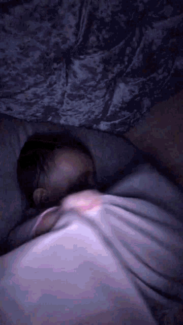 a person is sleeping under a blanket in a dark room .