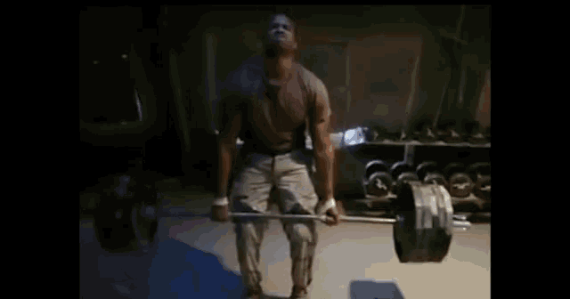 a man lifts a barbell in a dark room