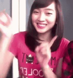 a woman in a pink shirt is giving a peace sign .