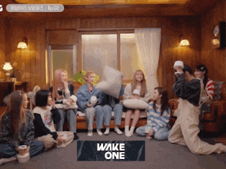 a group of women are sitting on a couch with a sign that says wake one on the floor