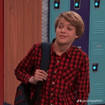 a young man in a plaid shirt is standing in front of lockers .