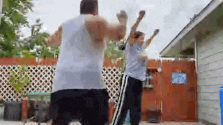 two men are standing next to each other in front of a fence .