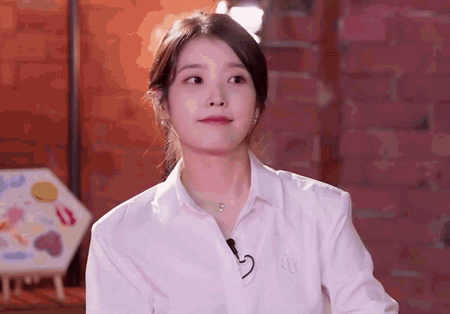 a woman wearing a white shirt with the letter k on the collar