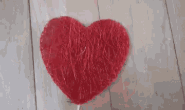 a red heart is sitting on top of a wooden table .