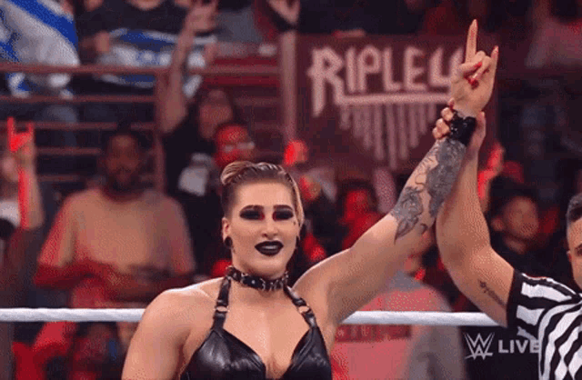 a woman in a wrestling ring with a referee giving her a high five