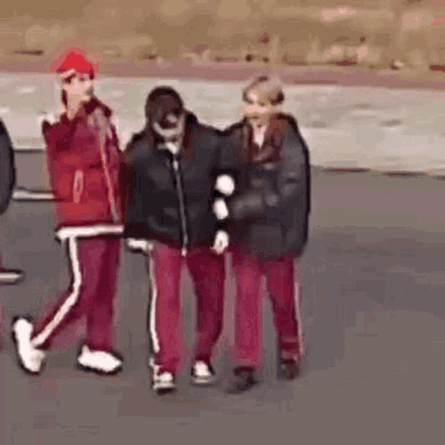 a group of people are walking down a street and one of them is holding another person 's arm .