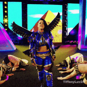 a woman in a blue and gold costume with wings is standing in front of a pyramid