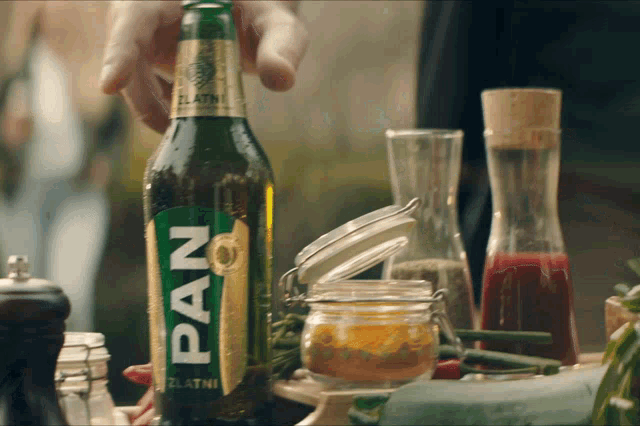 a bottle of pan sits on a table next to a jar of sauce