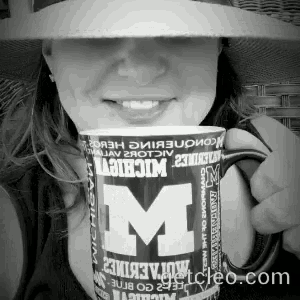 a woman in a hat is holding a mug that says michigan