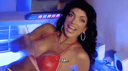 a woman in a red bikini is sitting in a tanning booth and says `` i tan '' .