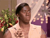 a woman is making a funny face while standing in front of a vase of flowers .