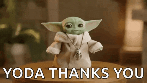 a baby yoda doll is sitting on a wooden table with the words `` yoda thanks you '' written below it .