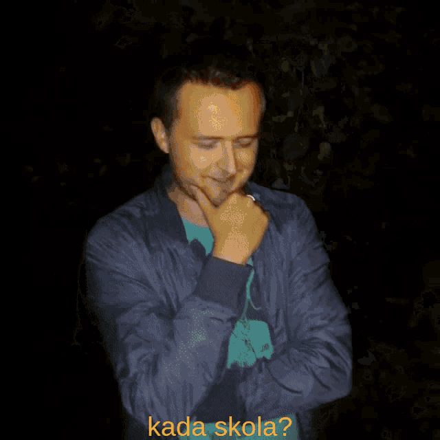 a man wearing a blue nike shirt is laughing with the words kada skola written in yellow