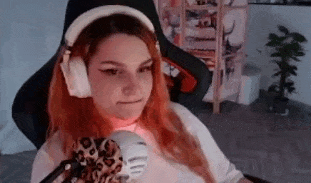 a woman is sitting in a chair wearing headphones and holding a stuffed animal .