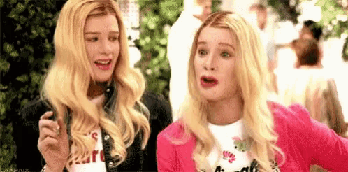 two blonde women are standing next to each other with their mouths open and making funny faces .