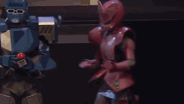 a woman in a pink costume is standing next to a blue robot .