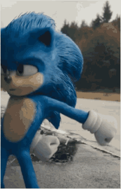 a blue sonic the hedgehog is standing on a concrete surface