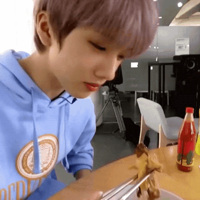 a young boy is sitting at a table eating a meal with chopsticks .