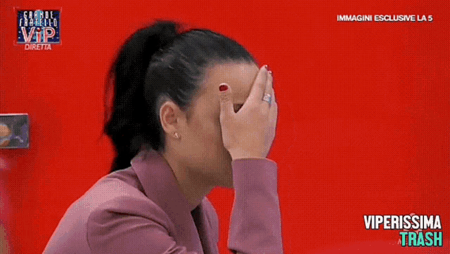 a woman covering her face with her hand in front of a red background that says vip on it