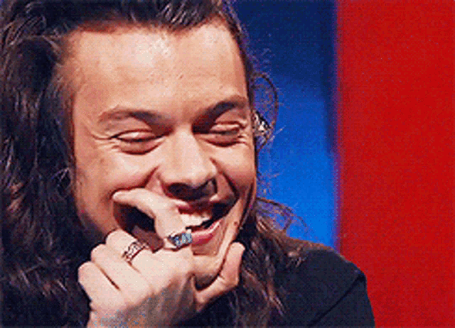 a man with long hair and a ring on his finger is laughing