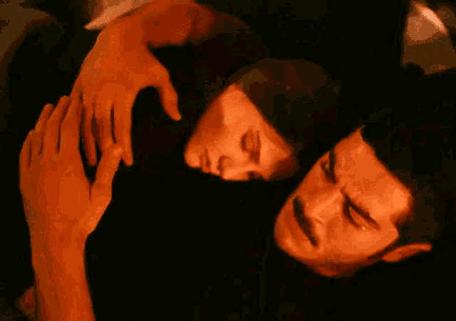 a man and a woman are laying on a bed with their eyes closed