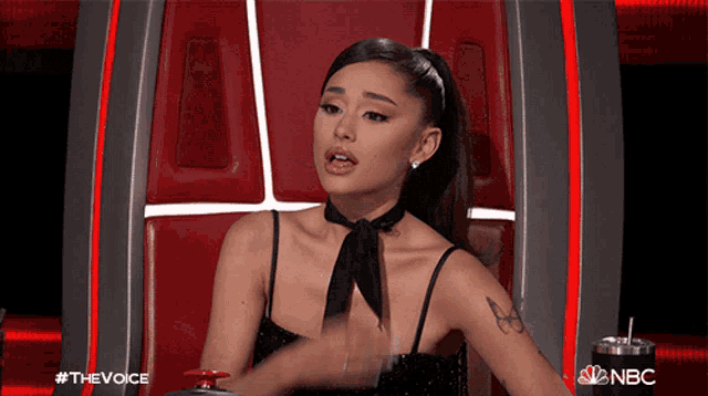 a woman in a black dress is sitting in a chair with a nbc logo in the corner