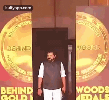 a man is standing in front of two gold coins that say behind woods medals