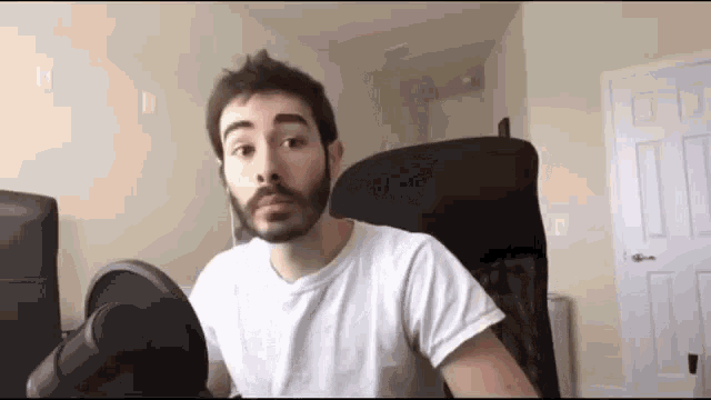 a man with a beard is sitting in a chair in a living room .