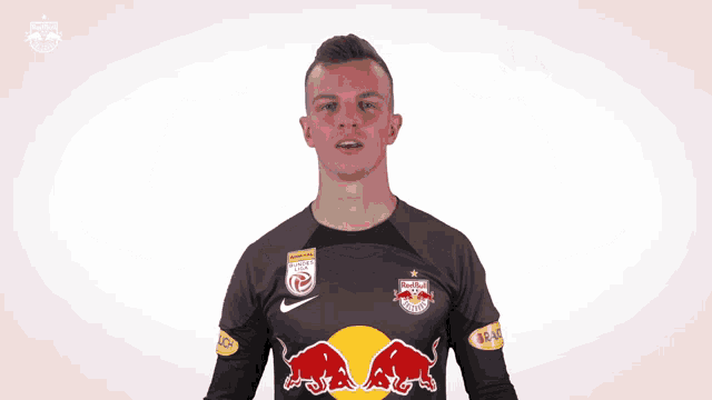 a man wearing a red bull jersey holds his arms out
