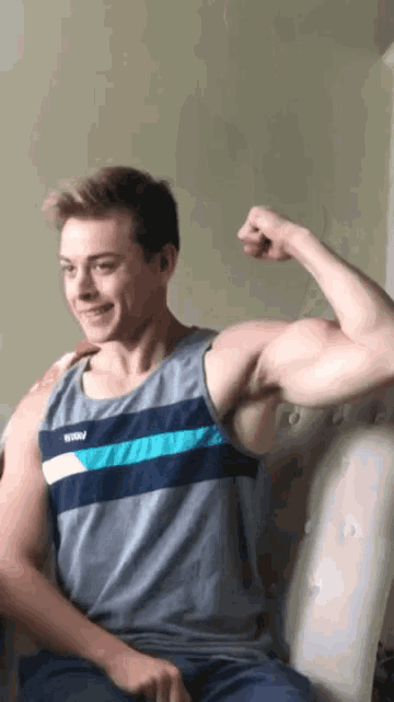 a man flexing his muscles while wearing a tank top that says ' abercrombie & fitch ' on it