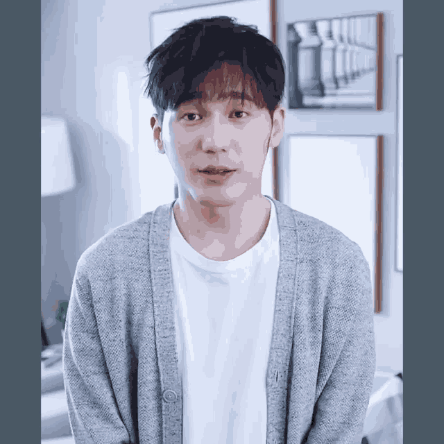 a young man wearing a grey cardigan and white shirt