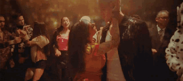 a man and a woman are dancing in a crowded room at a party .
