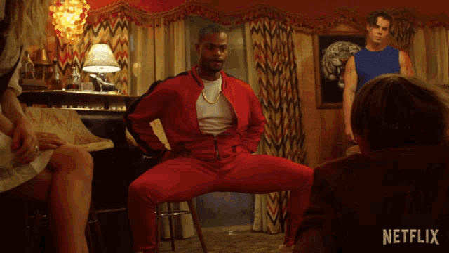 a man in a red jacket is dancing in a room with a netflix logo in the corner