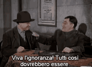 two men are sitting at a table and talking to each other .