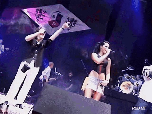 a man and a woman singing into microphones on a stage with rbd.gif written on the bottom