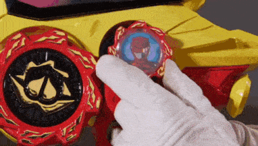 a person wearing a white glove is holding a red and yellow toy .