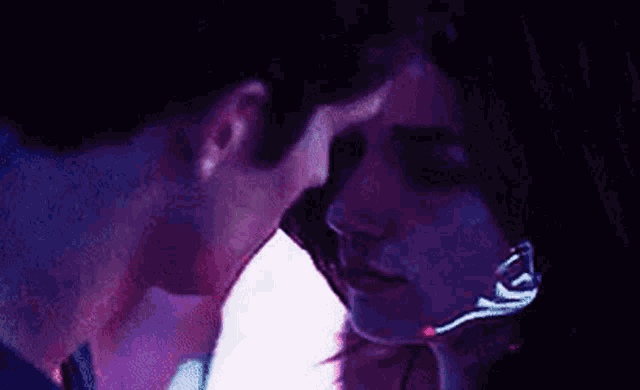 a man and a woman are kissing in the dark .