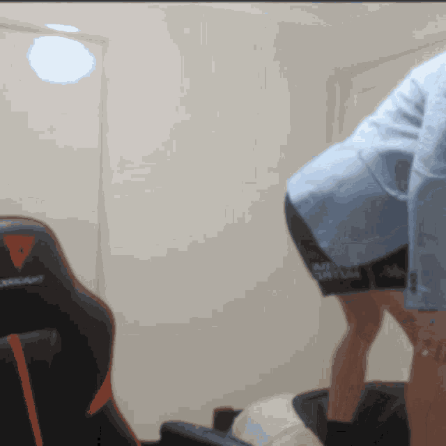 a person is standing in front of a black and orange gaming chair that says corsair on it
