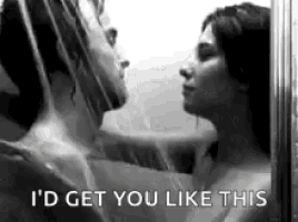 a man and a woman are kissing under a shower head .