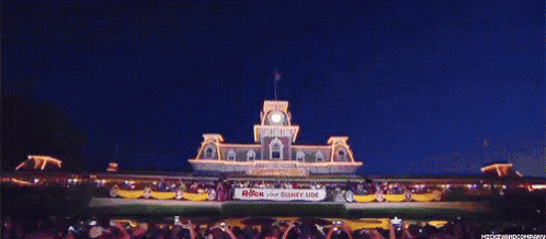 a crowd of people are standing in front of a large building at night taking pictures .