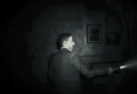 a woman is walking down a set of stairs in a dark room with a flashlight .