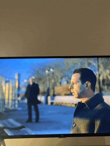 a tcl tv shows a man in a coat