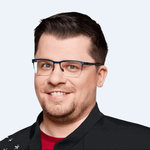 a man wearing glasses and a black jacket with stars on the sleeves smiles for the camera
