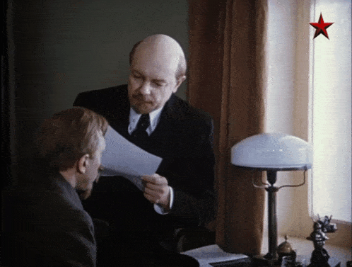 a man holding a piece of paper next to another man with a red star above him