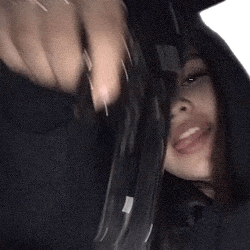 a woman is holding a gun in front of her face and smiling .