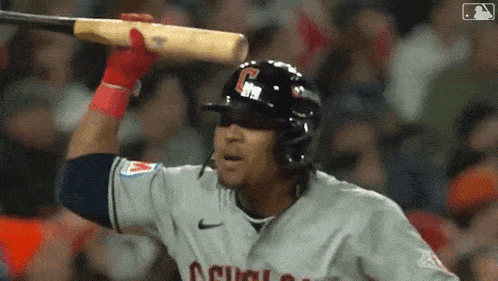 a baseball player with the letter c on his helmet holds his bat over his head