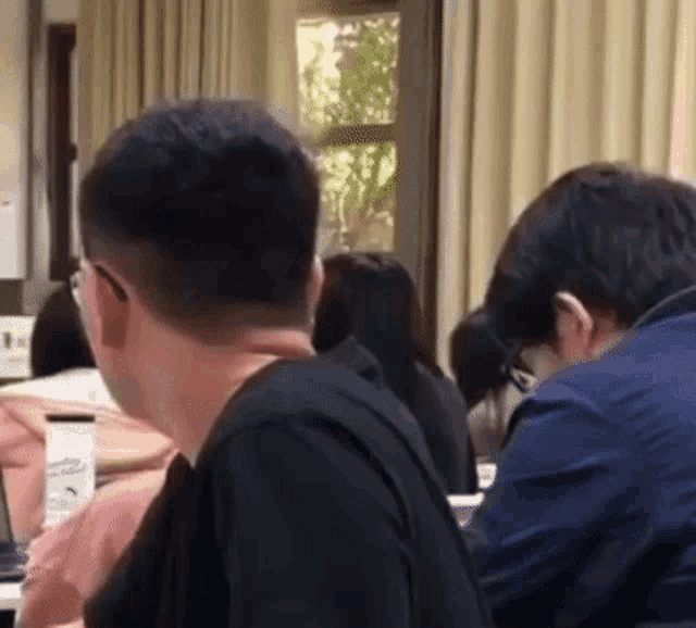 a group of people are sitting in a classroom looking at each other .