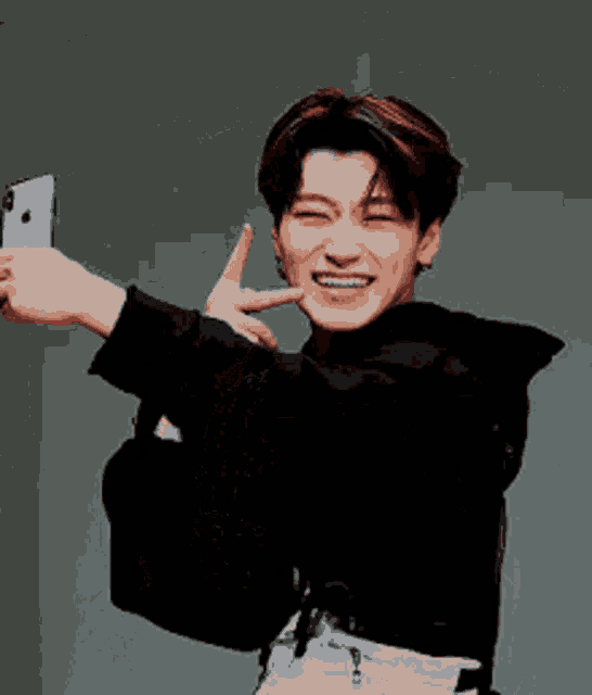 a young man is taking a selfie with a cell phone and smiling .